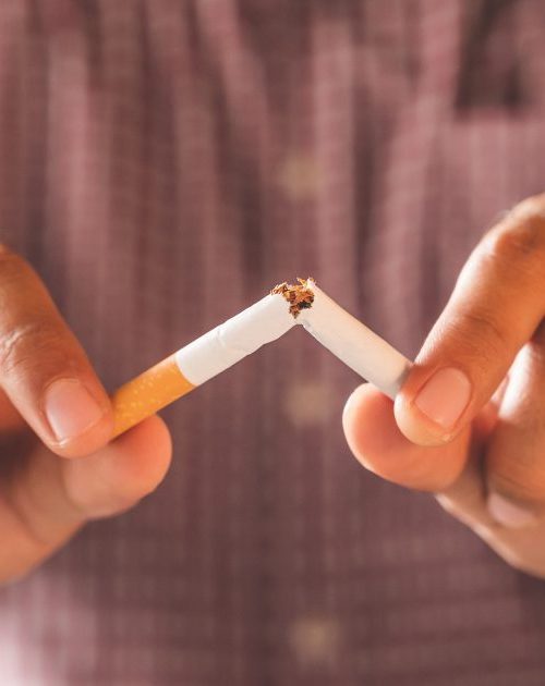 Photo avec un focus des mains d'un homme qui casse une cigarette en deux