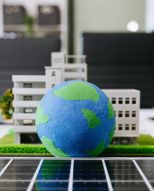 Image d'une maquette sur un bureau composée de la Terre, d'immeubles et de verdure